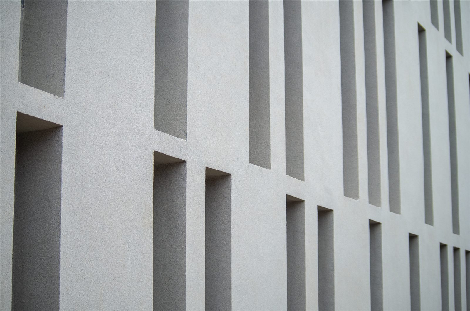 Recessed institutional facade with a consistent Luxstone texture finish